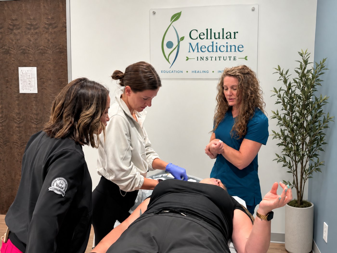 CMI faculty and trainees performing hands-on neural therapy instruction in front of the Cellular Medicine Institute sign